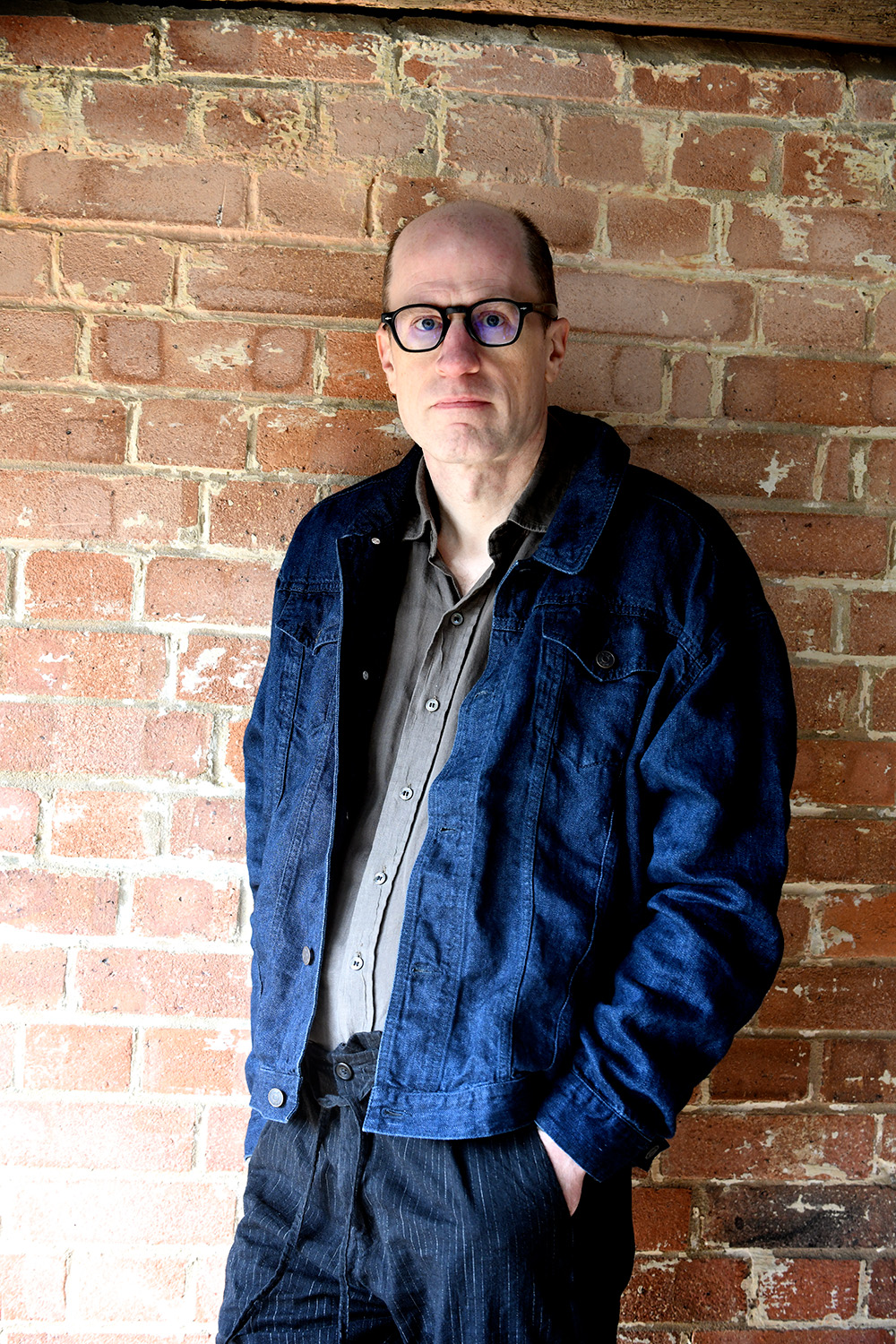 Outdoors portrait of Nick Bostrom against a brick wall