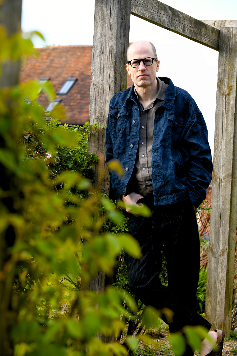 Outdoors portrait of Nick Bostrom among greenery and a wooden structure